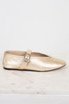 Gold metallic flat shoe with a strap on a light background
