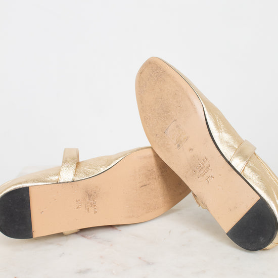 Bottom soles of gold shoes on a white marble surface