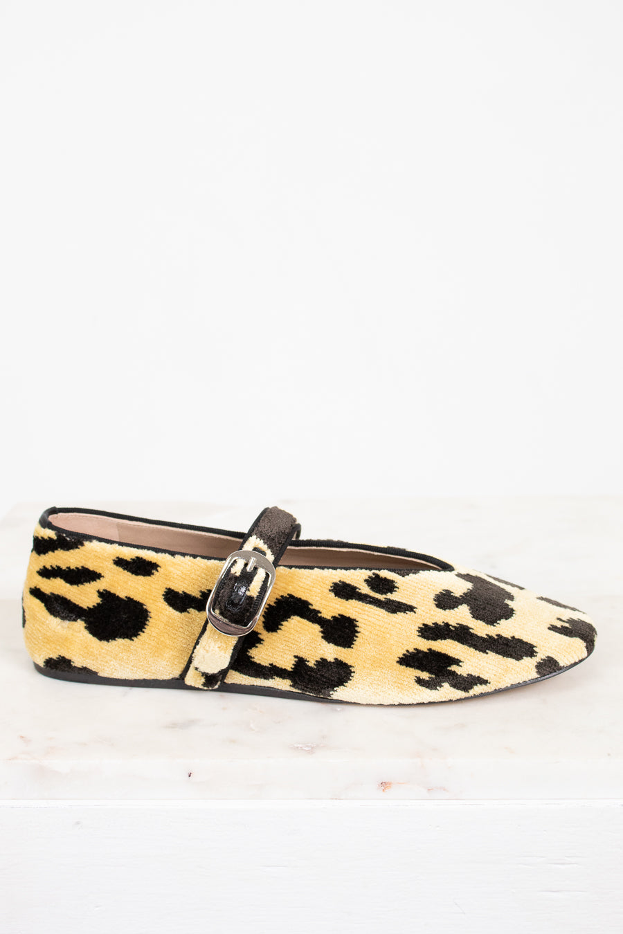 Leopard print flat shoe with a strap on a white background