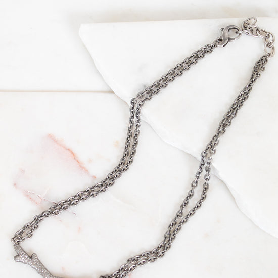 Silver necklace with diamond brand detail on white background