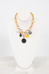 Gold necklace with various colored charms on a white stand