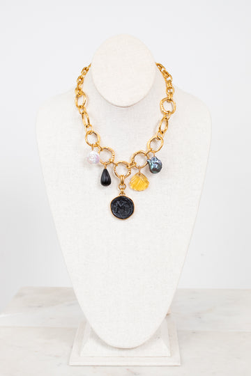 Gold necklace with various colored charms on a white stand