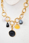 Gold chain necklace with various charms on a white background