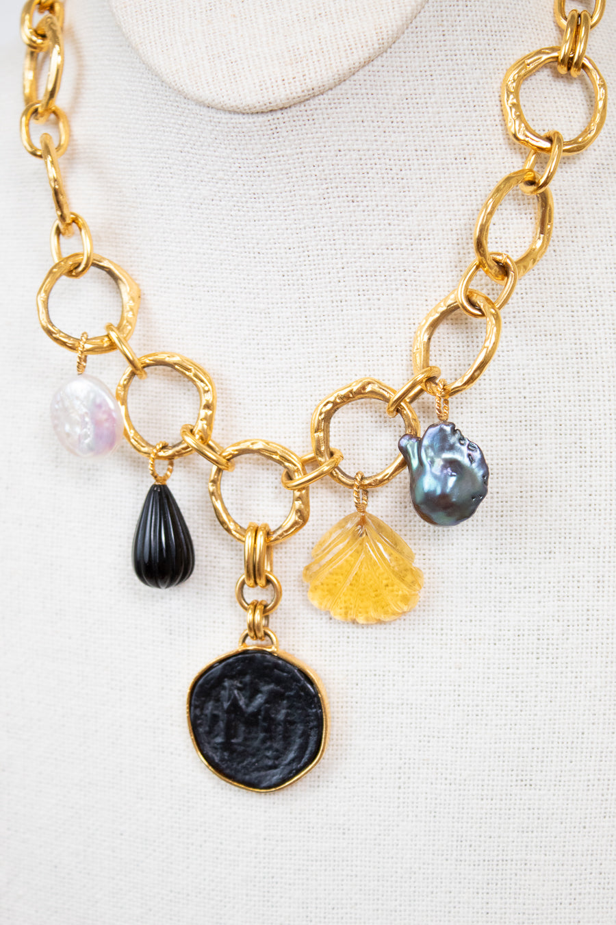 Gold chain necklace with various charms on a white background