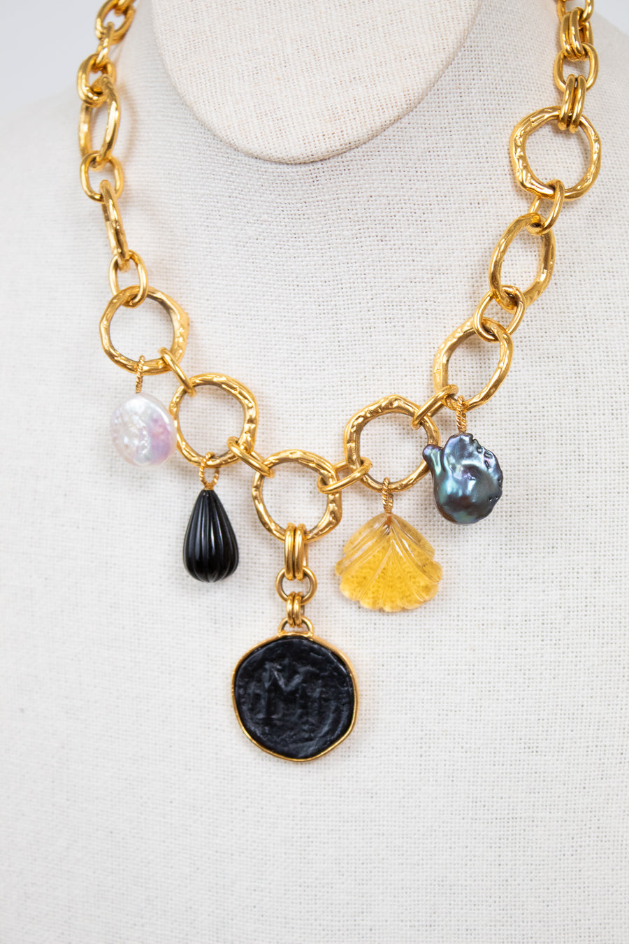 Gold chain necklace with various charms on a white background