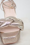 Silver glitter high heel shoe with a braided design on a light background