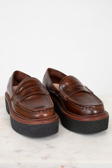 Pair of brown loafers with thick black soles on a light background