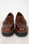 Pair of brown loafers with black soles on a light background