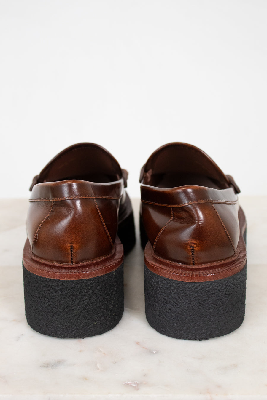 Pair of brown leather shoes with black soles on a light background