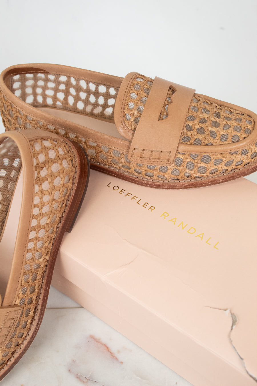 Tan loafers with woven design on a marble surface with 'LOEFFLER RANDALL' branded box.