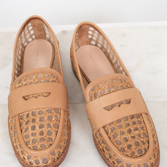 Pair of tan loafers with decorative pattern on a light background