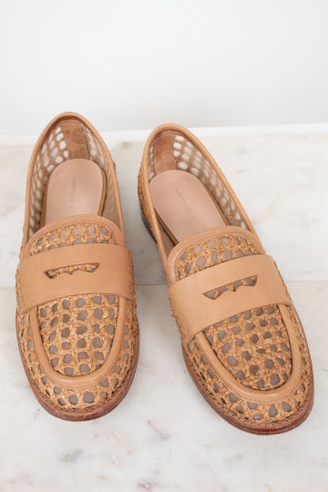 Pair of tan loafers with decorative pattern on a light background