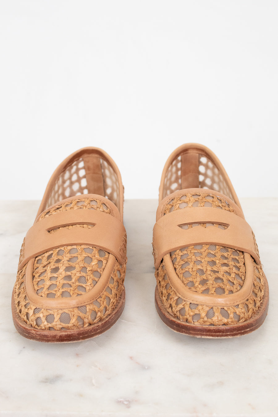 Pair of tan woven loafers on a light background