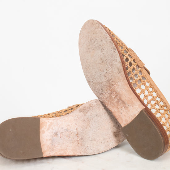 Bottom sole of a pair of flat shoes with woven design on a white marble surface