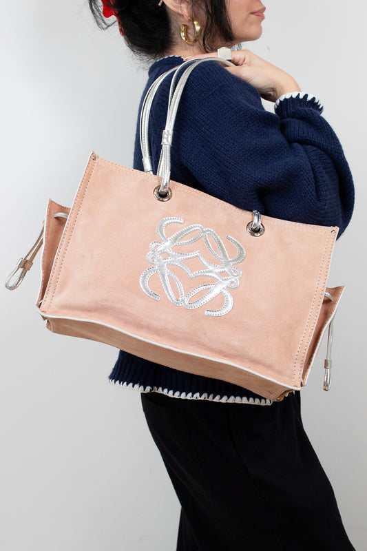 Person holding a beige tote bag with a logo against a white background