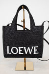 Black woven handbag with 'LOEWE' branding on a stand against a white background