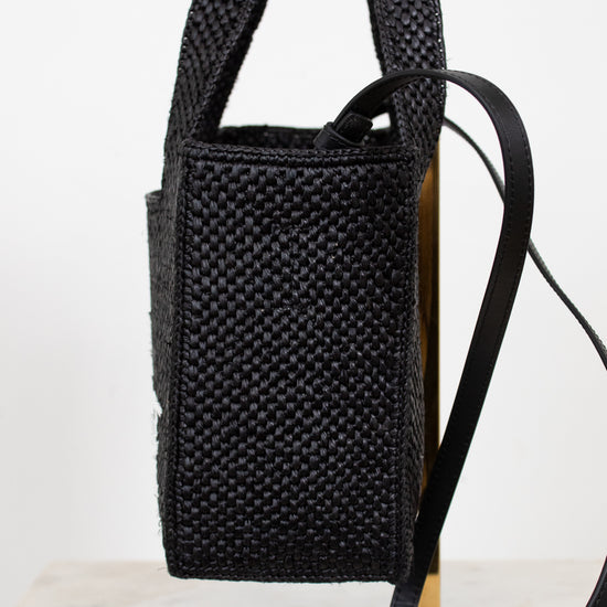 Black woven handbag with a strap on a white background