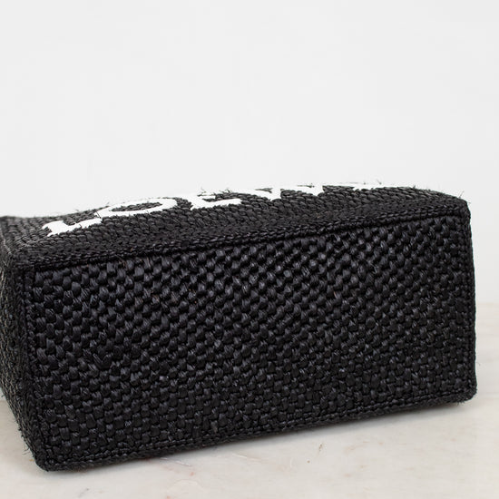 Black woven handbag on a marble surface with a white background