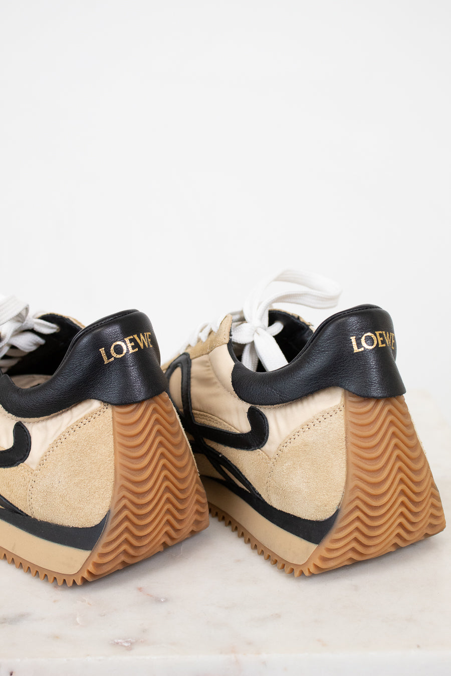 Pair of tan sneakers with black accents on a light background