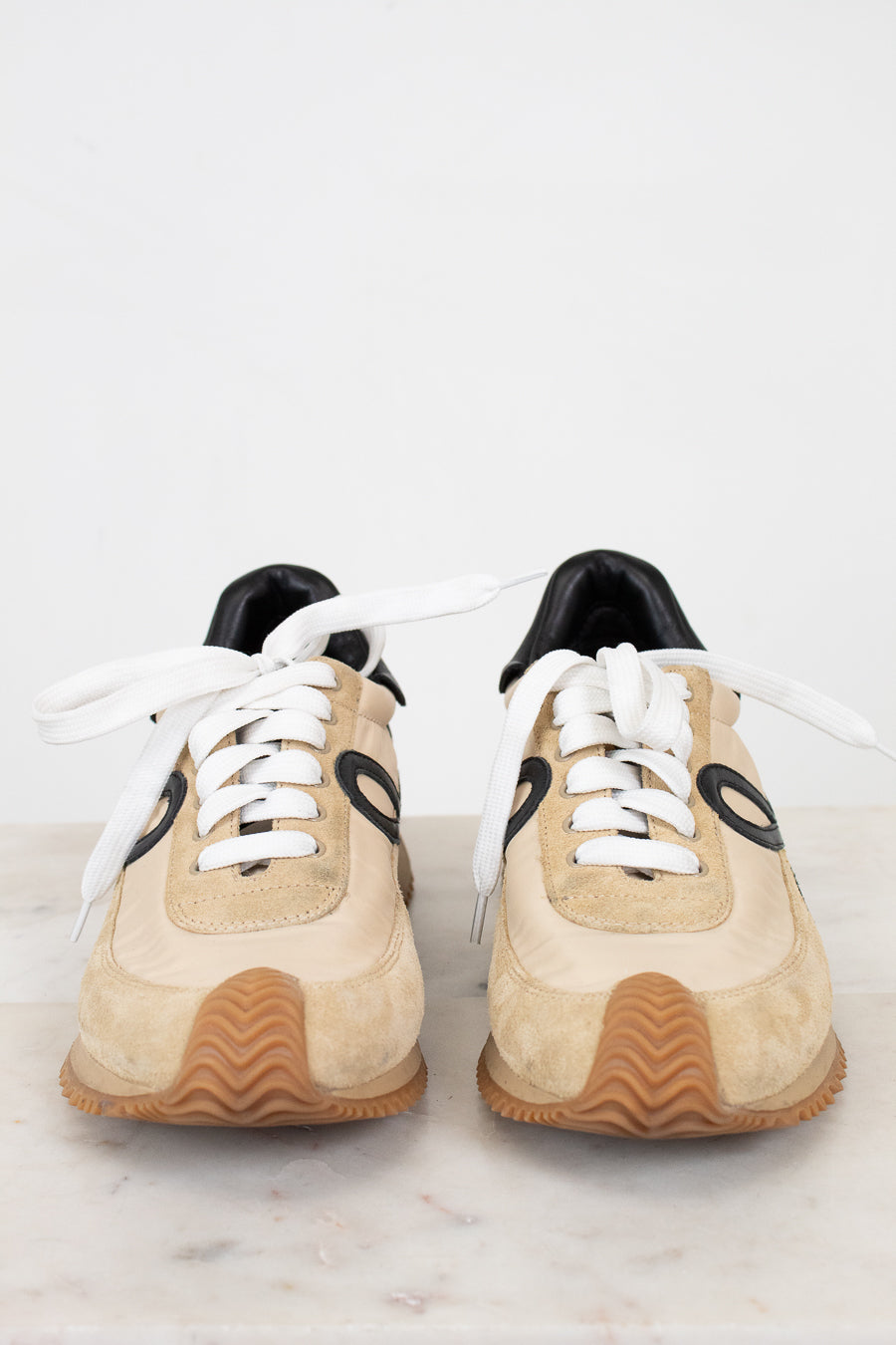 Pair of beige sneakers with black accents on a light gray background