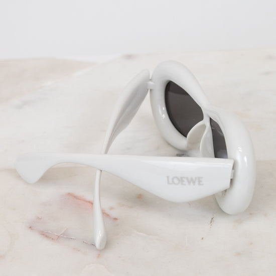 White sunglasses with 'Loewe' branding on a marble surface