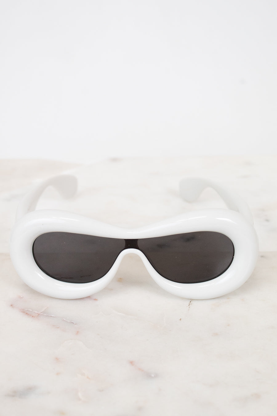 White sunglasses with black lenses on a marble surface