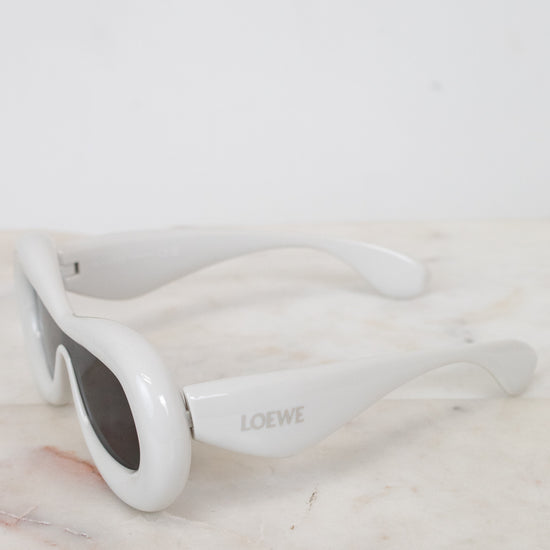 White sunglasses with 'Loewe' branding on a marble surface
