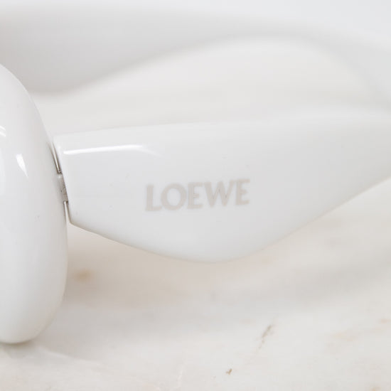 White sunglasses with 'LOEWE' branding on a marble surface