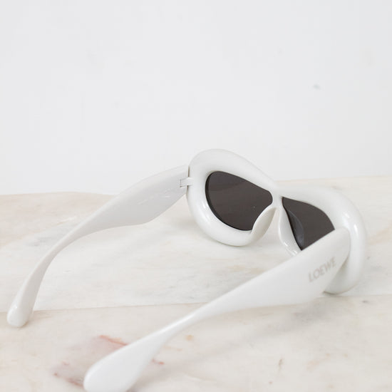 White sunglasses with dark lenses on a light marble surface