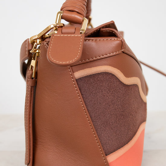 Brown leather handbag with gold accents on a white background