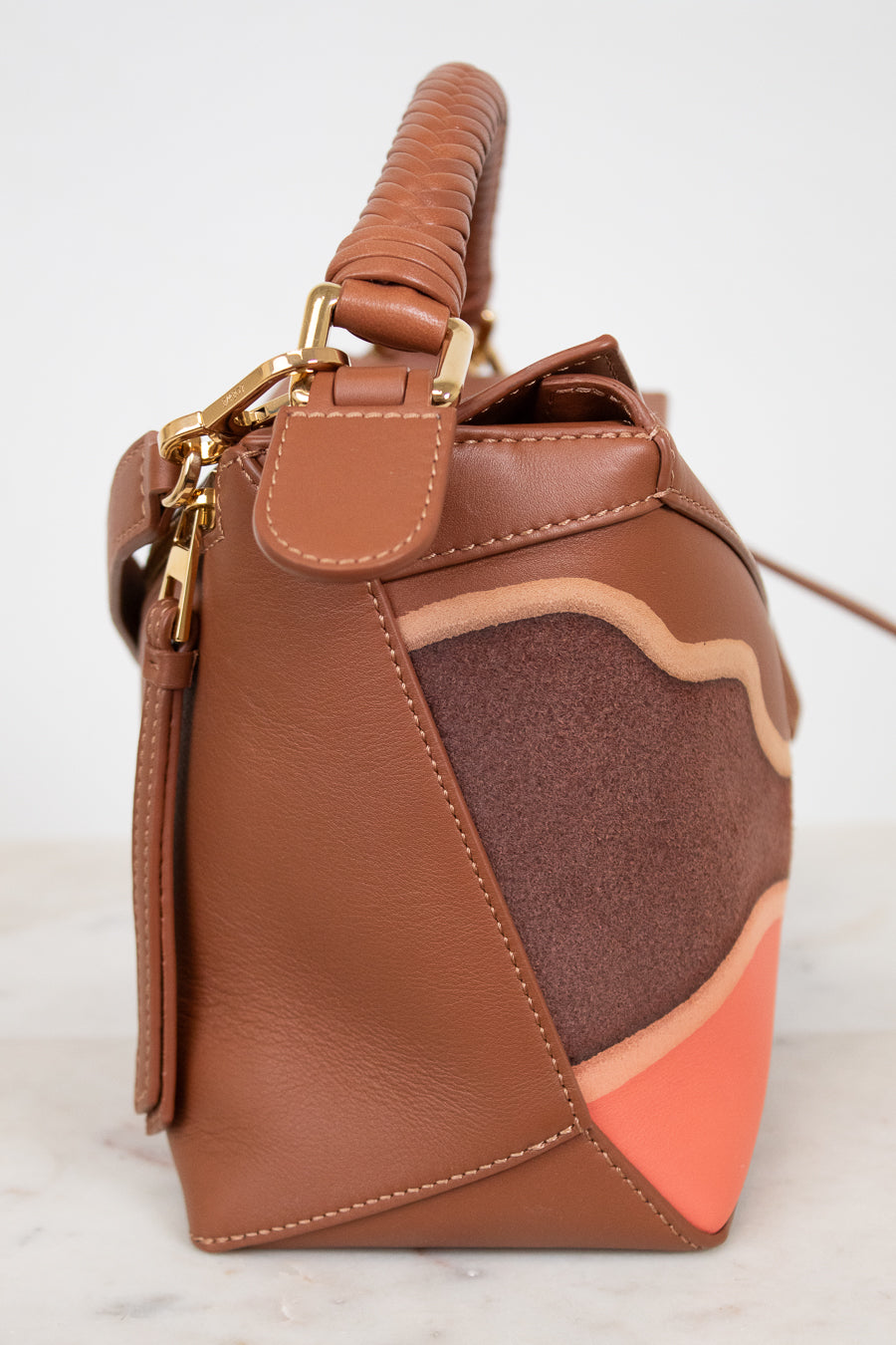Brown leather handbag with gold accents on a white background