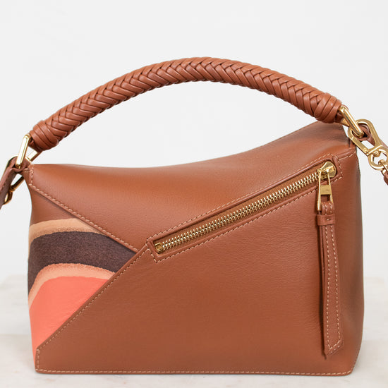 Brown handbag with a braided handle on a white background