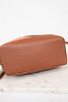 Brown leather handbag on a marble surface with a white background