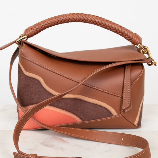 Brown leather handbag with a braided handle on a white background