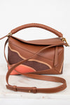 Brown leather handbag with a braided handle on a white background