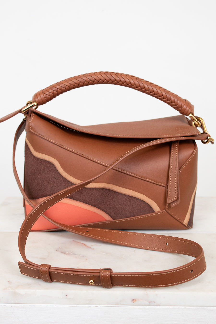 Brown leather handbag with a braided handle on a white background