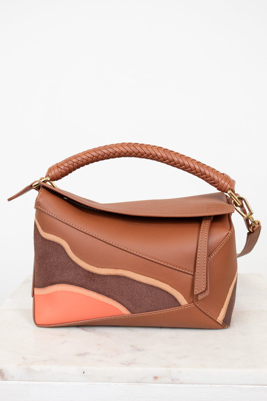 Brown handbag with a braided handle on a white background