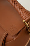 Close-up of a brown leather handbag with braided handle and gold clasp.