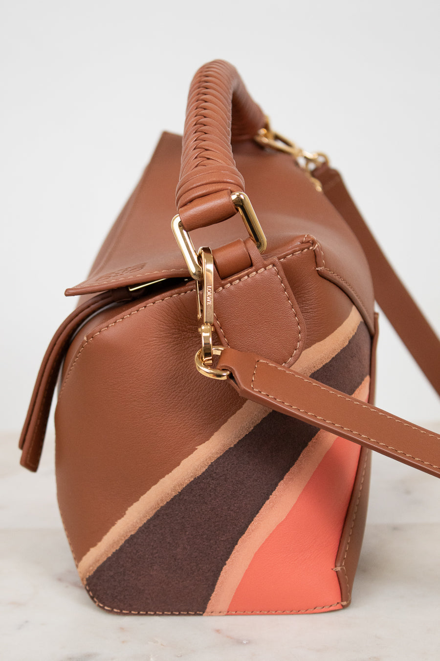 Brown handbag with a gold clasp on a light background