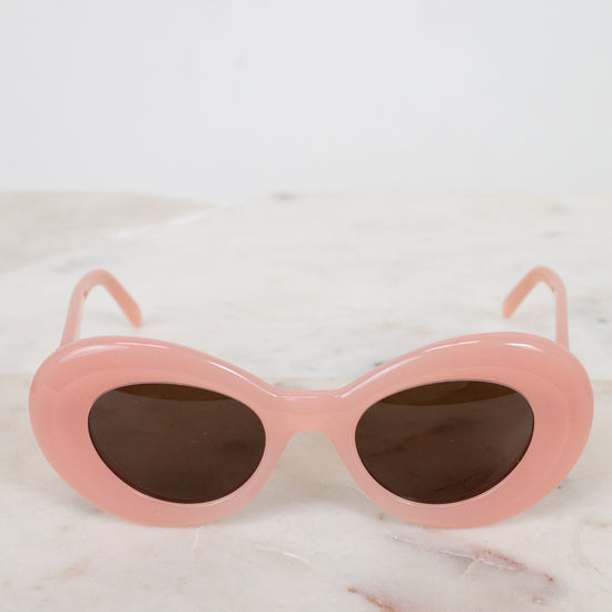 Pink sunglasses with dark lenses on a marble surface
