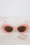 Pink sunglasses with dark lenses on a marble surface
