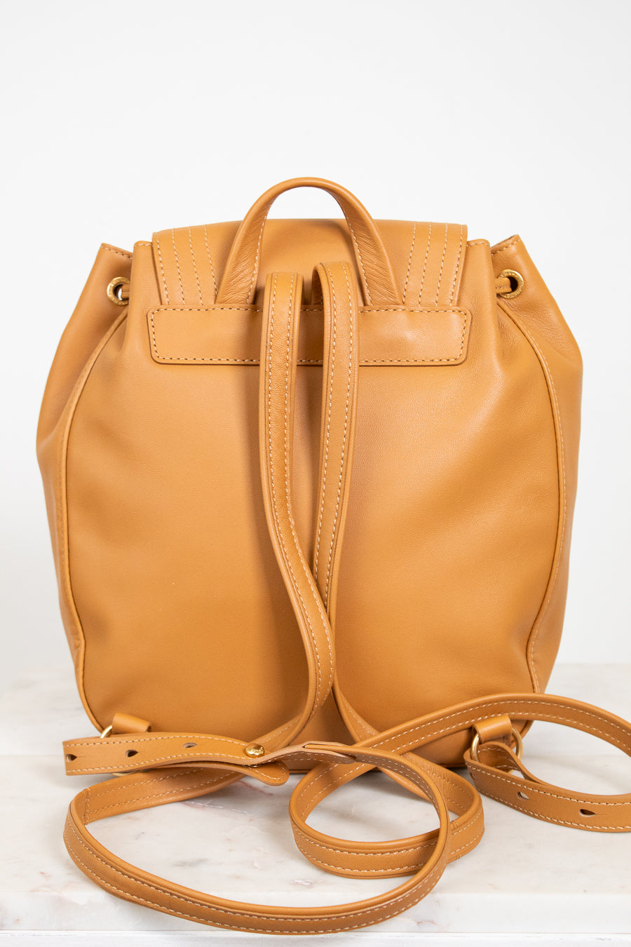 Tan leather backpack with a strap on a white background