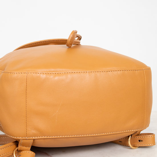 Tan leather backpack on a light marble surface