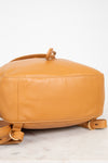 Tan leather backpack on a light marble surface