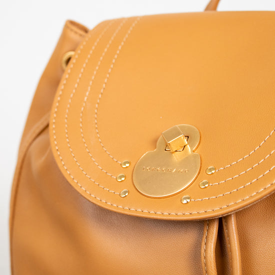 Tan leather backpack with a gold lock on a light gray background