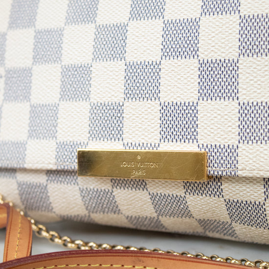 Close-up of a checkered handbag with a gold tag on a marble surface