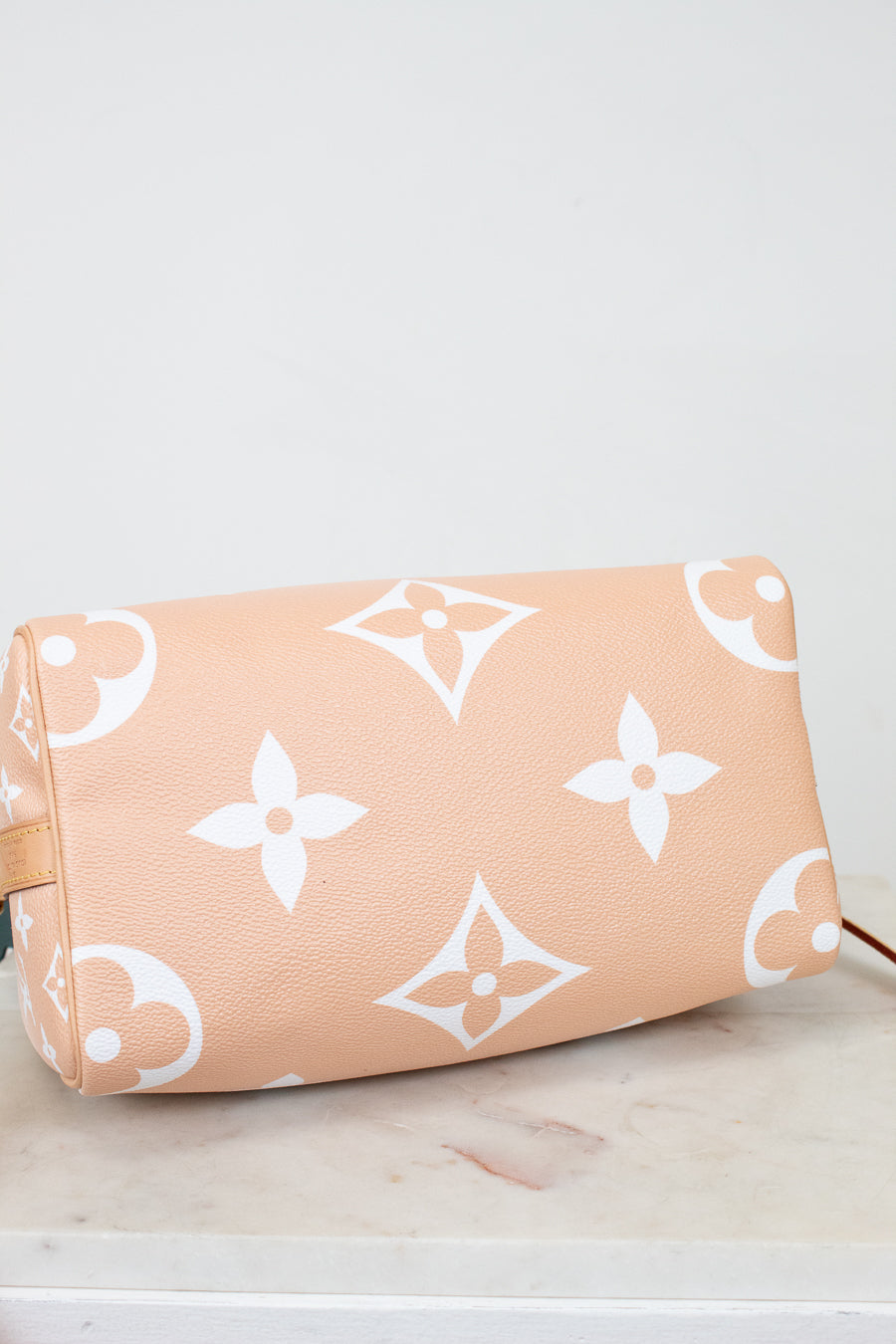 Base of Louis Vuitton bag with logo pattern on a light background