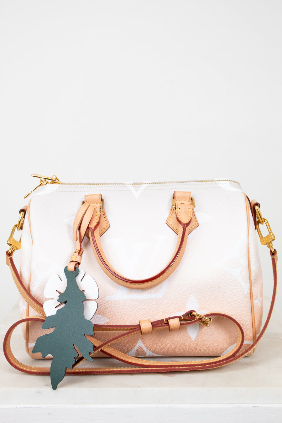 White handbag with brown strap and gold hardware on a white background