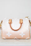 Designer handbag with a white logo pattern on a light background