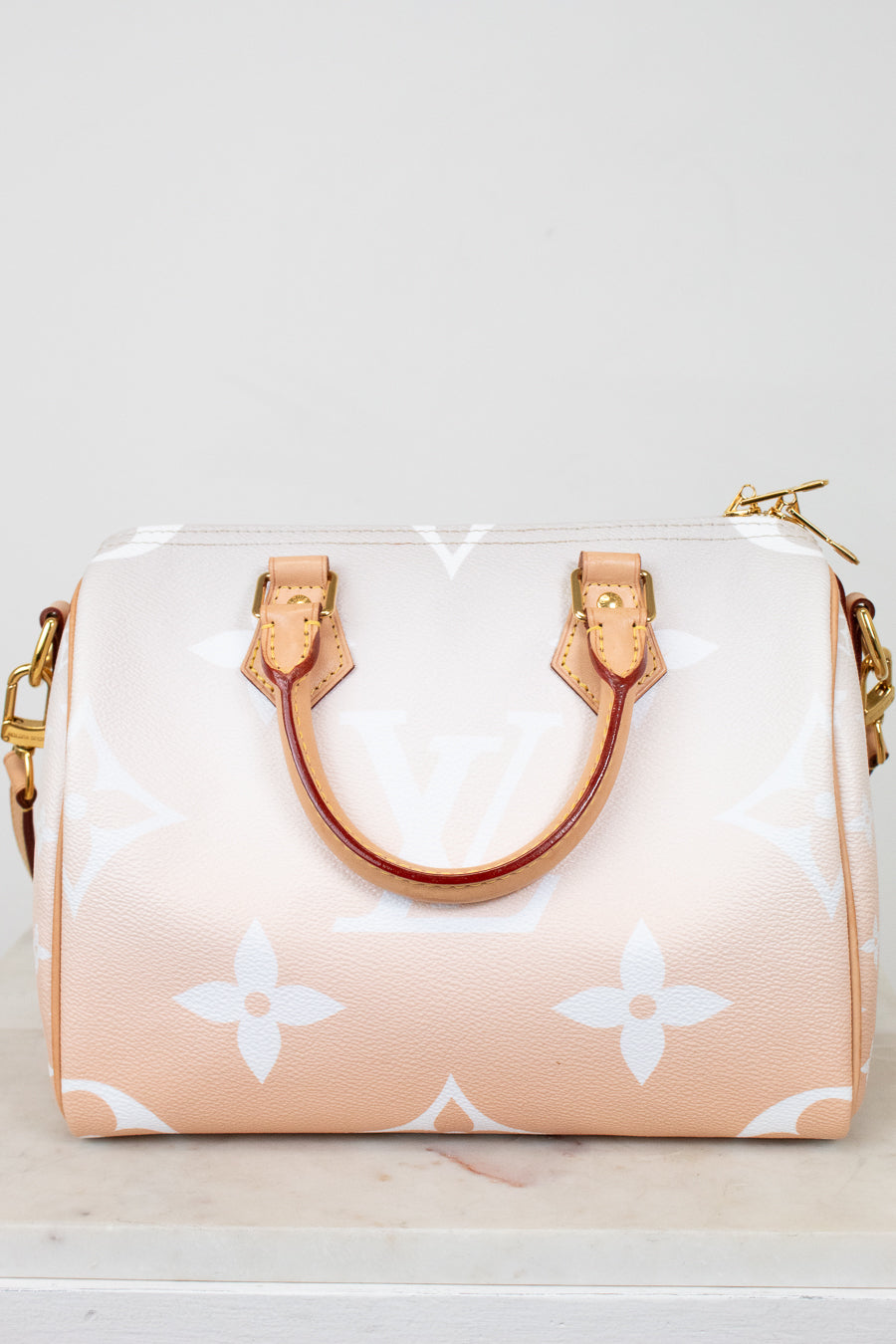 Designer handbag with a white logo pattern on a light background